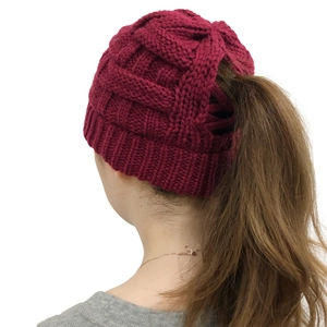 Detail view of dark red ponytail knit beanie with textured grid pattern and ribbed edge