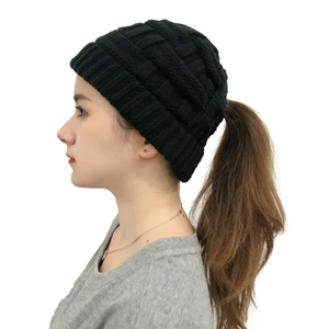 Detail of black cable knit ponytail beanie showing the opening for long hair on a model