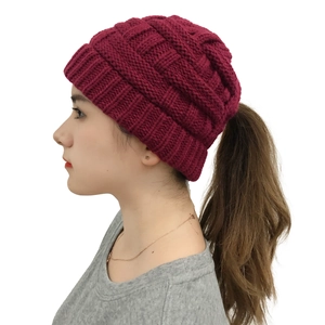 Close-up of wine red knitted beanie featuring a ponytail hole and textured grid pattern