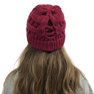 Detail of burgundy knit beanie featuring a cross-pattern hole for high ponytails