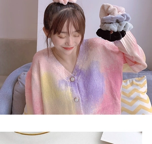 Detailed view of plush scrunchies in beige, gray, and black worn on a model's wrist