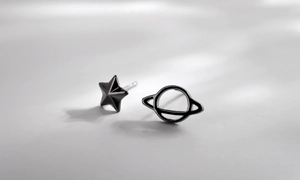Macro detail of asymmetrical S925 silver star and planet studs in black silver finish