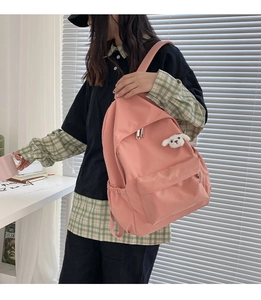 Dettaglio zaino in nylon rosa con un simpatico ciondolo a forma di cucciolo di peluche