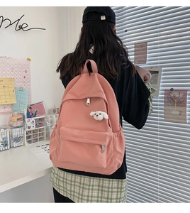 Zaino in nylon rosa impermeabile con ciondolo a cucciolo carino in una scena di scrivania