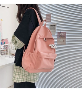 Zaino rosa in tela impermeabile con ciondolo a forma di pecora indossato da modella