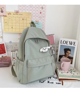 Dettaglio dello zaino in nylon verde impermeabile con ciondolo a forma di cucciolo