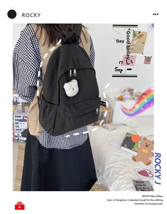 Dettaglio dello zaino in nylon nero con tasche laterali per bottiglie d'acqua e ciondolo