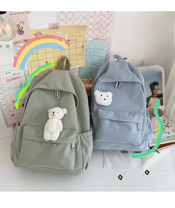 Dettaglio di zaini in nylon impermeabile verde chiaro e blu con ciondoli a orsetto