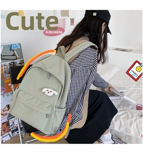 Dettaglio dello zaino in nylon verde chiaro impermeabile con spilla a forma di cucciolo di peluche