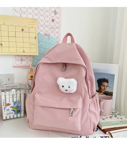Dettaglio dello zaino in nylon rosa impermeabile con orsetto su una scrivania