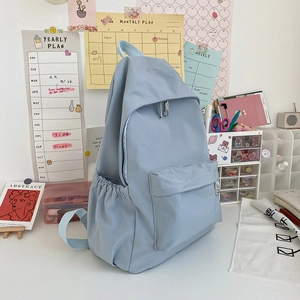 Dettaglio dello zaino in nylon azzurro impermeabile sulla scrivania con calendario