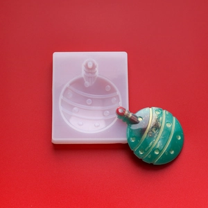 Macro shot of green Christmas ornament silicone mold with finished resin striped bauble