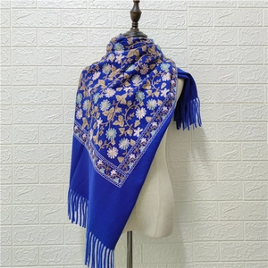 Detail of blue faux cashmere scarf with intricate floral embroidery and tassel fringe
