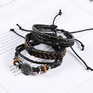 Close-up of retro layered leather bracelets set with metal charms on vintage paper