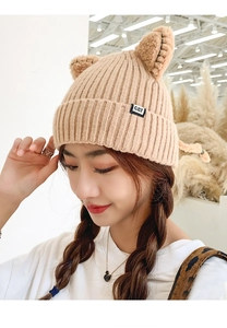 Detailed close-up of beige knit winter hat featuring cute cat ears and CAT side label