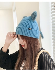 Detail of blue knitted beanie with cute cat ears and black CAT label for winter