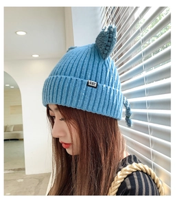 Detailed close-up of blue knitted cat ear hat featuring a white CAT woven side label