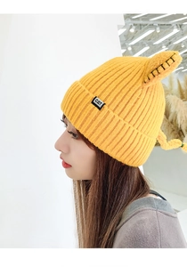 Detail view of the yellow knitted hat with cute cat ears and black CAT woven label