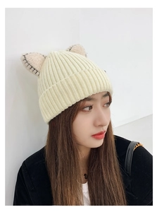 Detail shot of a beige winter knit hat featuring cute cat ears and soft wool texture