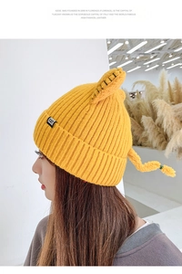 Detail of yellow knit beanie with cute cat ears and CAT label for winter warmth