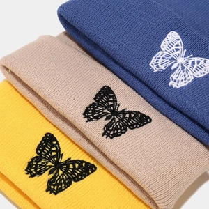 Close-up of butterfly embroidery details and knit texture on colorful beanies