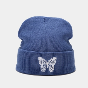 Close-up of blue knit beanie featuring detailed white butterfly embroidery on the cuff