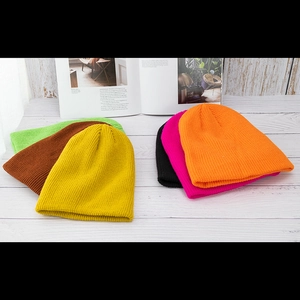 Minimalistische Strickmützen in verschiedenen Farben auf weißer Holzoberfläche