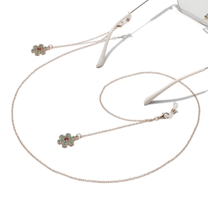 Detail of gold metal eyewear chain with festive snowflake charms and colorful crystals