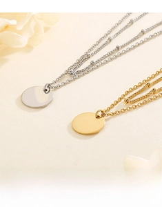 Detail of layered gold and silver necklaces with round pendants on a minimalist background