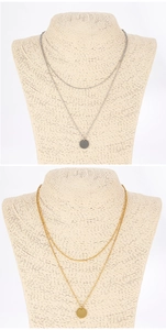 Detail of layered gold and silver necklaces with round pendants on a mannequin