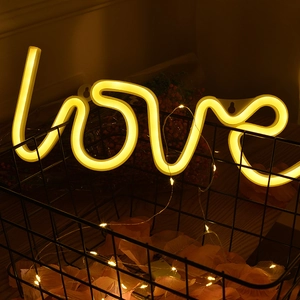 Warm yellow LED neon LOVE sign in black wire basket with cozy romantic fairy lights