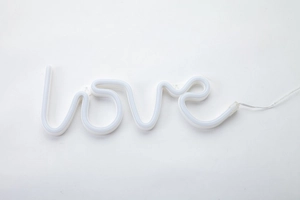 Detail of white flexible LED neon light strip shaped into the word love with clear cable