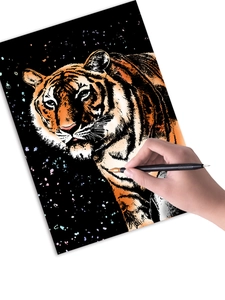 Gros plan d'une main gravant un tigre coloré sur du papier à gratter avec un stylet
