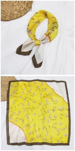 Dettaglio di un foulard di seta giallo a fiori con trama piegata e motivo steso a terra