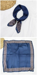Dettaglio di foulard in seta blu navy con motivi geometrici e trama lucida