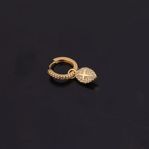 Détail d'une boucle d'oreille dorée avec pendentif feuille, motif étoile et zircons