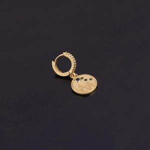 Détail de la boucle d'oreille dorée avec motifs lune, étoile et gemmes bleues