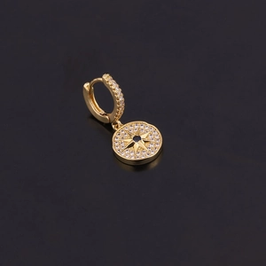 Détail de la boucle d'oreille dorée avec pendentif étoile et pierre précieuse bleue