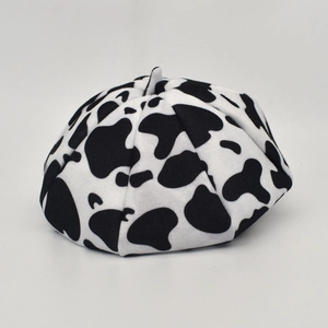 Close-up of wool beret with black and white cow print texture and classic top stem
