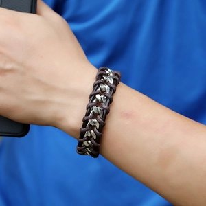 Close-up of brown woven leather cord and silver metal chain bracelet worn on wrist