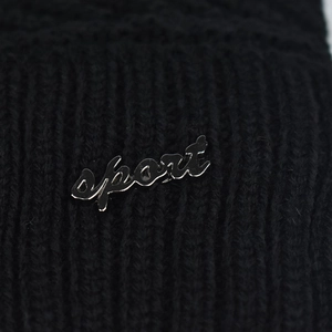 Vue détaillée du logo sport en métal argenté sur bonnet et écharpe en maille noire
