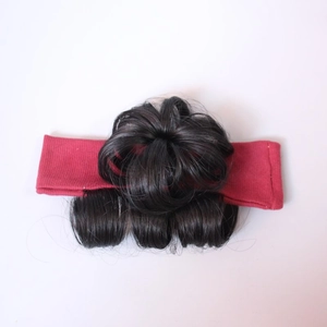 Detail of red fabric headband with integrated black curly synthetic hair bun for toddlers