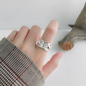Detailed view of silver irregular hammered texture ring worn on a finger