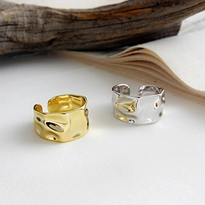 Detail of gold and silver S925 rings with hammered texture on a rustic background