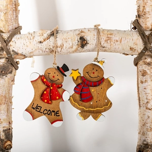 Hand-painted wooden gingerbread man ornaments with welcome text hanging on birch branches