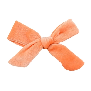 Close-up of coral velvet hair bow showing soft plush texture and handcrafted central knot