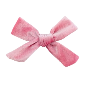 Detailed close-up of a pink velvet bow hair accessory with soft fabric texture