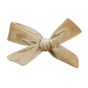 Detailed texture of velvet knot bow hair clip in champagne gold finish on white background
