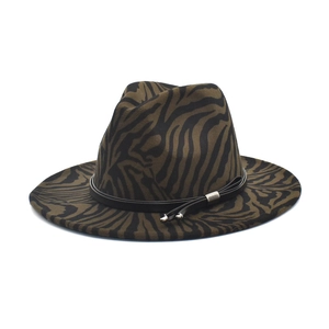 Détail d'un chapeau fedora en laine zébré avec lanière en cuir noir et gland métallique