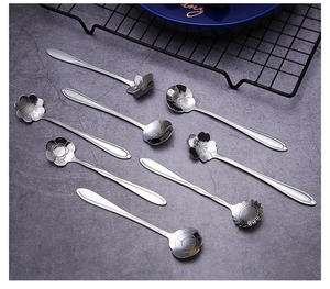 Detailed top view of assorted floral-shaped stainless steel spoons on a grey background